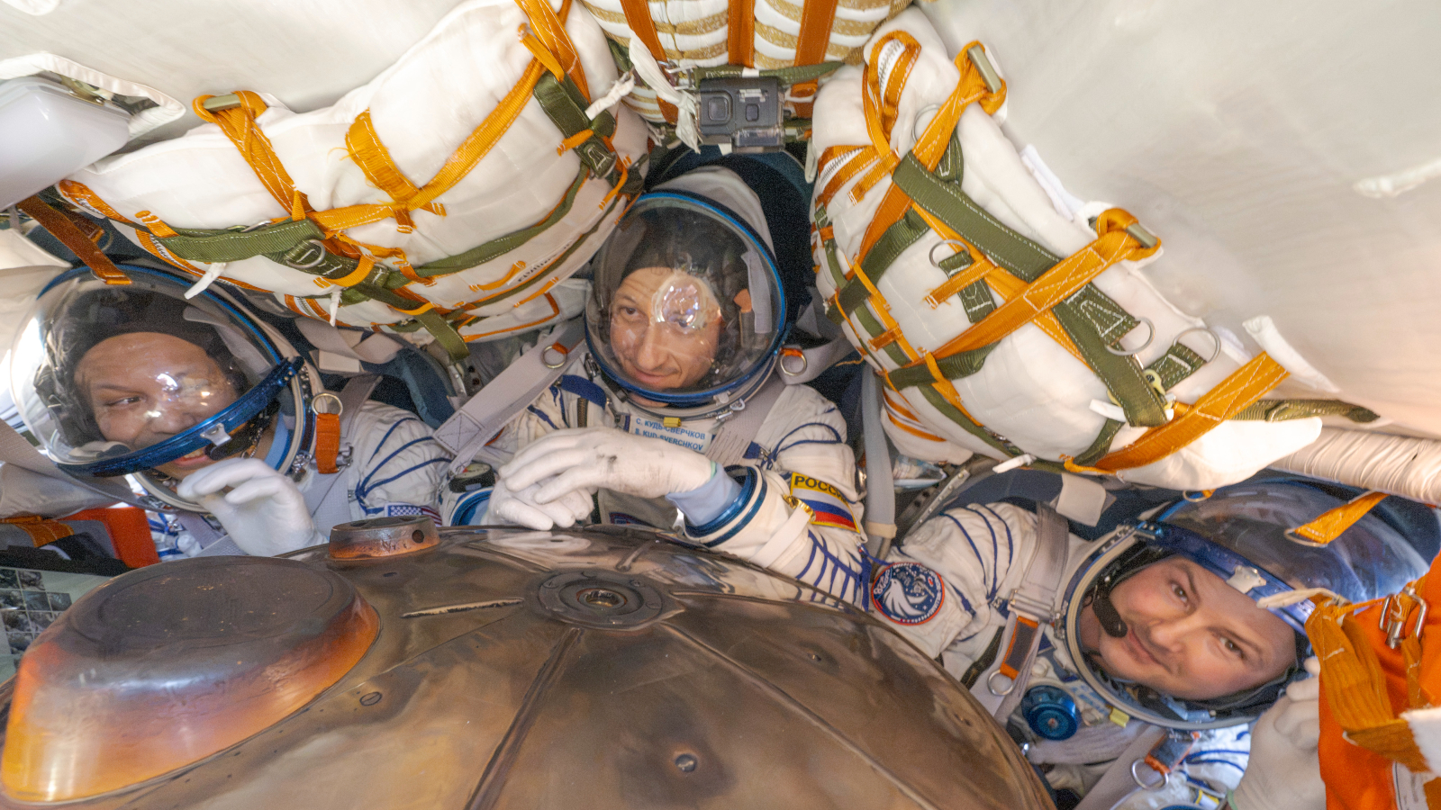 A photograph of three astronauts in a return capsule from the ISS