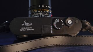 Leica M11-D camera on a dark blue table, low key lighting, top plate
