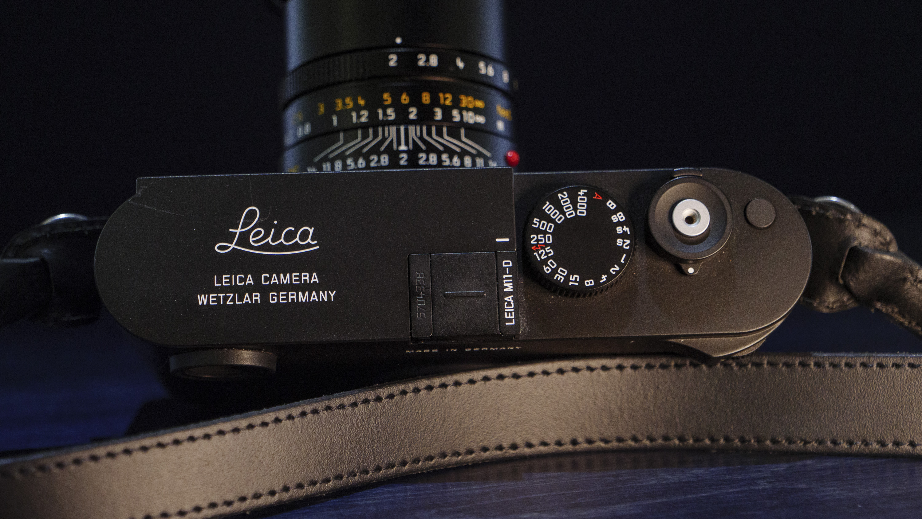 Leica M11-D camera on a dark blue table, low key lighting, top plate