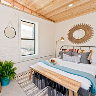 bedroom with white walls wooden flooring and wooden bed with mattress and piloows