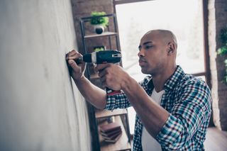 man using drill on wall