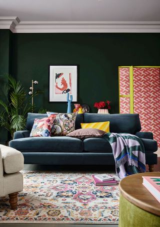 Green living room with plush sofa and patterned red wallpaper in the distance