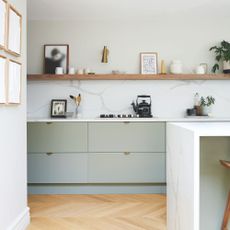 White painted kitchen with marble backsplash and light green cupboards underneath