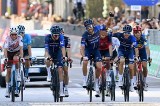 Thibaut Pinot waves to the crowd as he crosses the finish line with his Groupama-FDJ teammates on the final race of his career