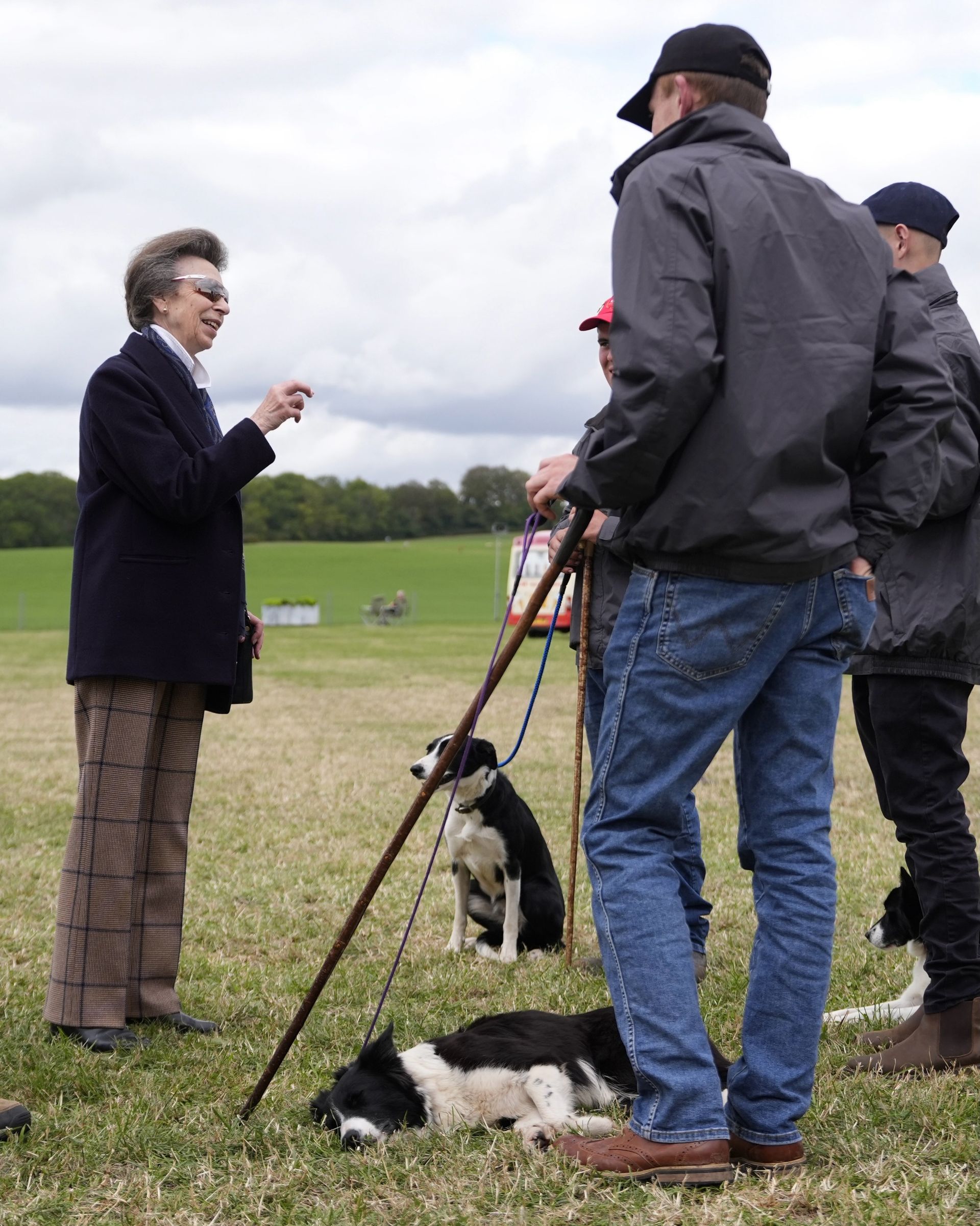 Princess Anne talking to men holding dogs on leashes