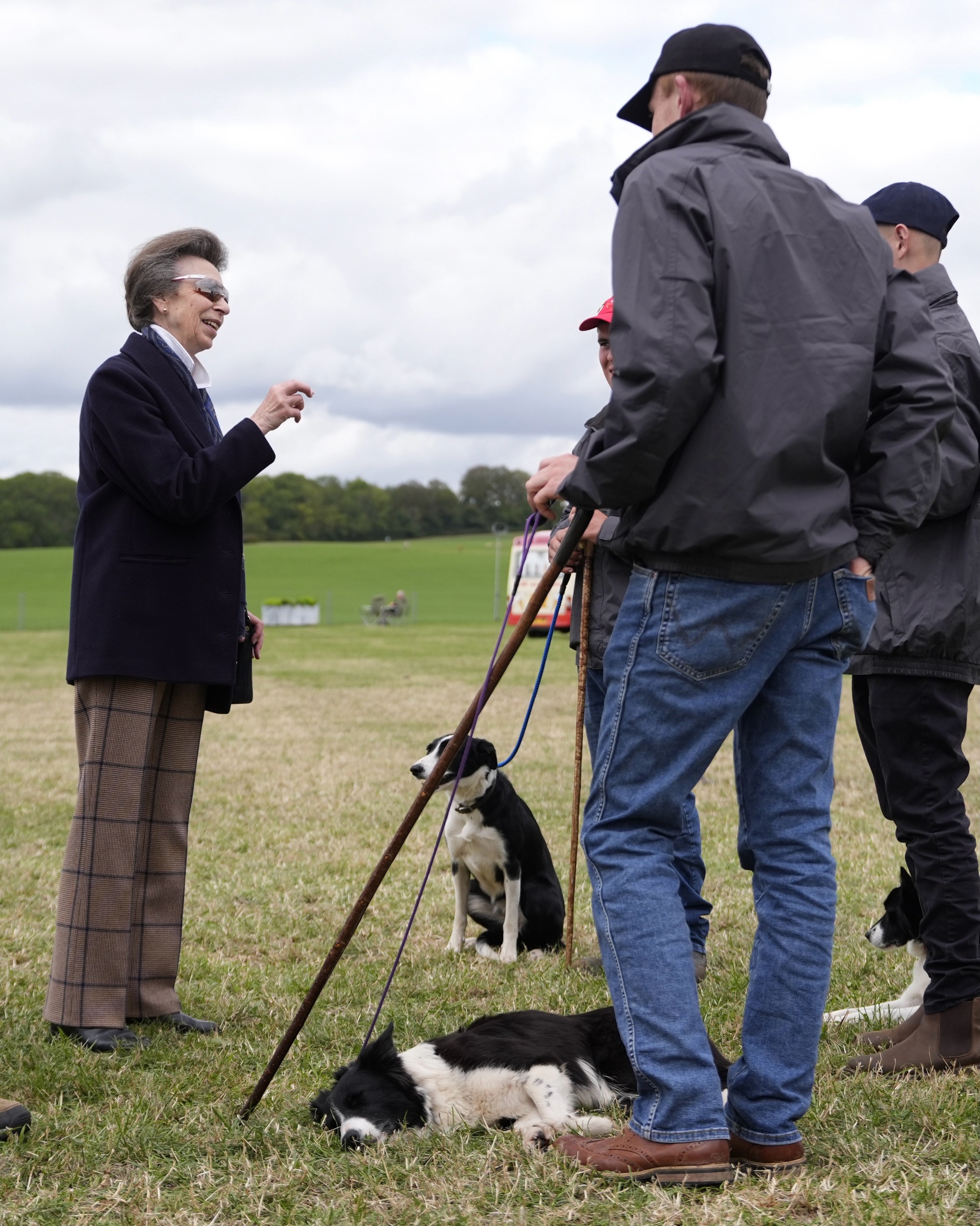 Princess Anne talking to men holding dogs on leashes