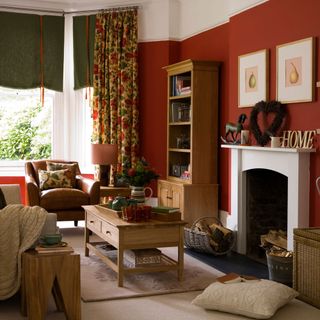 A country living room with red walls white fireplace and leather armchair with wooden furniture