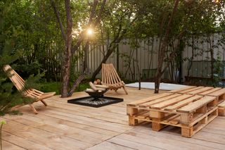 A deck with an outdoor fire and chairs.