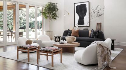 white living room with vaulted ceiling, monochromatic scheme, wooden floors, outdoor space through doors, modern furniture, black pendant light