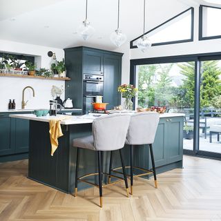 kitchen with wood herringbone floor and blue island and cabinetry and glass patio doors