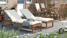 an acacia wood sun lounger with a white cushion in a backyard