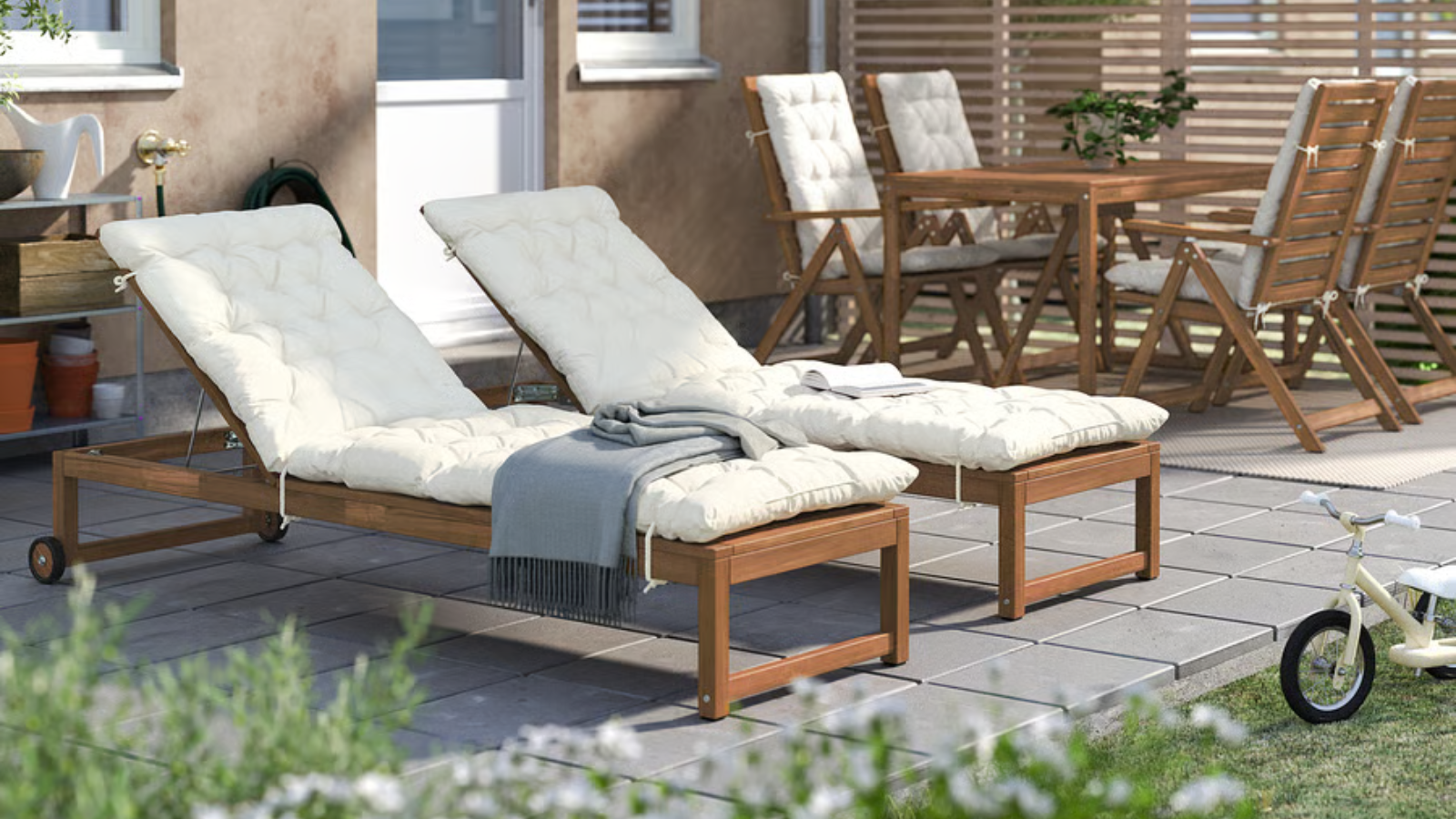 an acacia wood sun lounger with a white cushion in a backyard