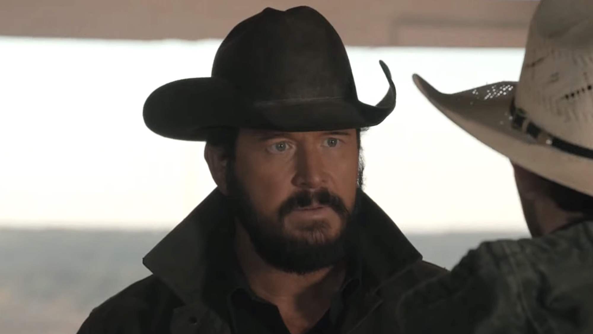 Rip in hat staring intently at Carter in stable in Dutton Ranch Season 1