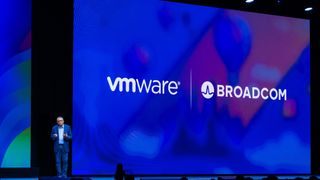Raghu Raghuram, CEO at VMware by Broadcom, stood on stage at VMware Explore Barcelona 2023. Behind him, the old VMware logo and the Broadcom logo are displayed on a massive keynote screen.