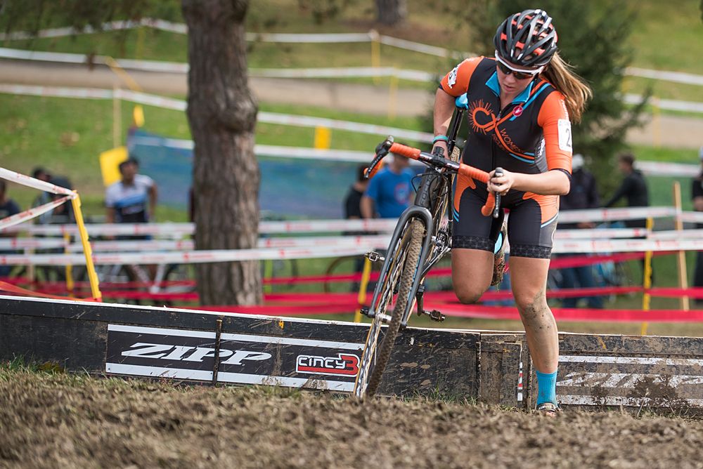 A Women CX Project rider makes her way over a muddy set of barriers during the final two laps of racing.