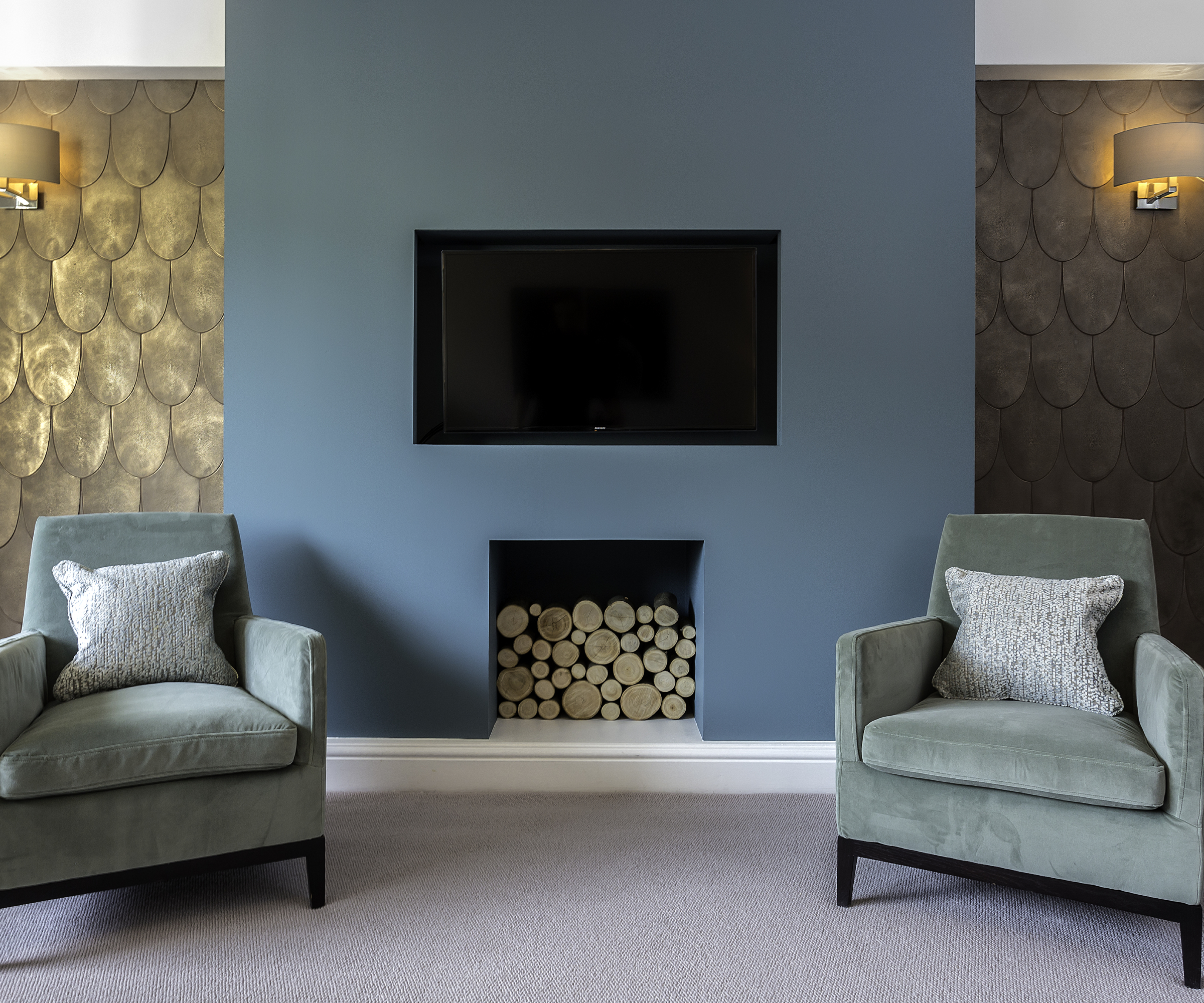living room with feature wall in blue, gold patterned metallic wallpaper and two arm chairs in pale turquoise