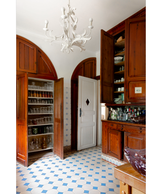 Wooden kitchen with blue and white tile floor and statement white pendant