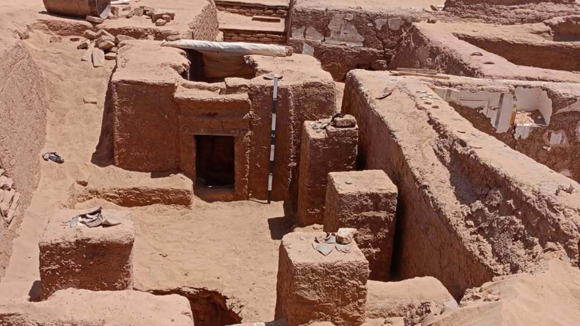 A zoomed out view of a half-unearthed tomb in the desert.