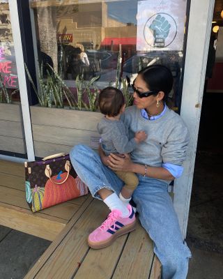 Aimee Song wearing jeans, Adidas sneakers, a blue button down shirt, a grey sweater, Louis Vuitton bag, and black sunglasses.