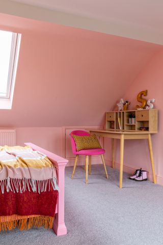 A pink toned bedroom with a study nook in an alcove