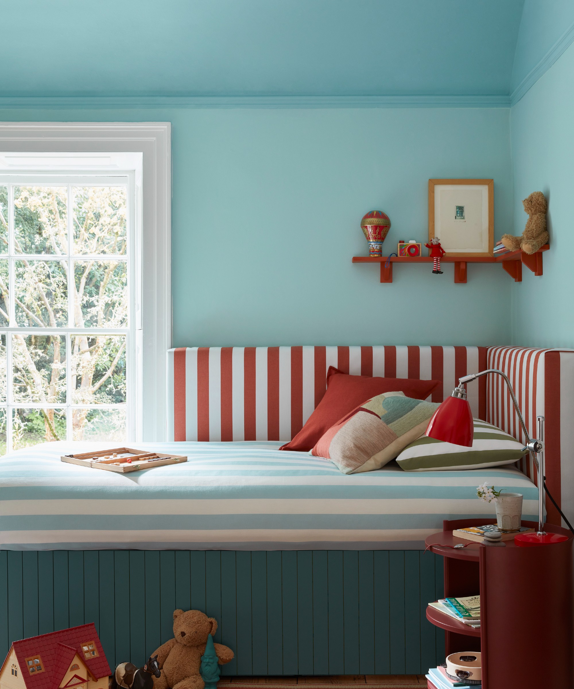 A double-drenched kids' bedroom painted in blue with a ceiling in a different shade of blue and a striped bed in blue, red and white