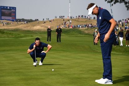 Ian Poulter helps team-mate Rory McIlroy line up a putt. Difference Between Fourball and Foursomes GettyImages-1042442856