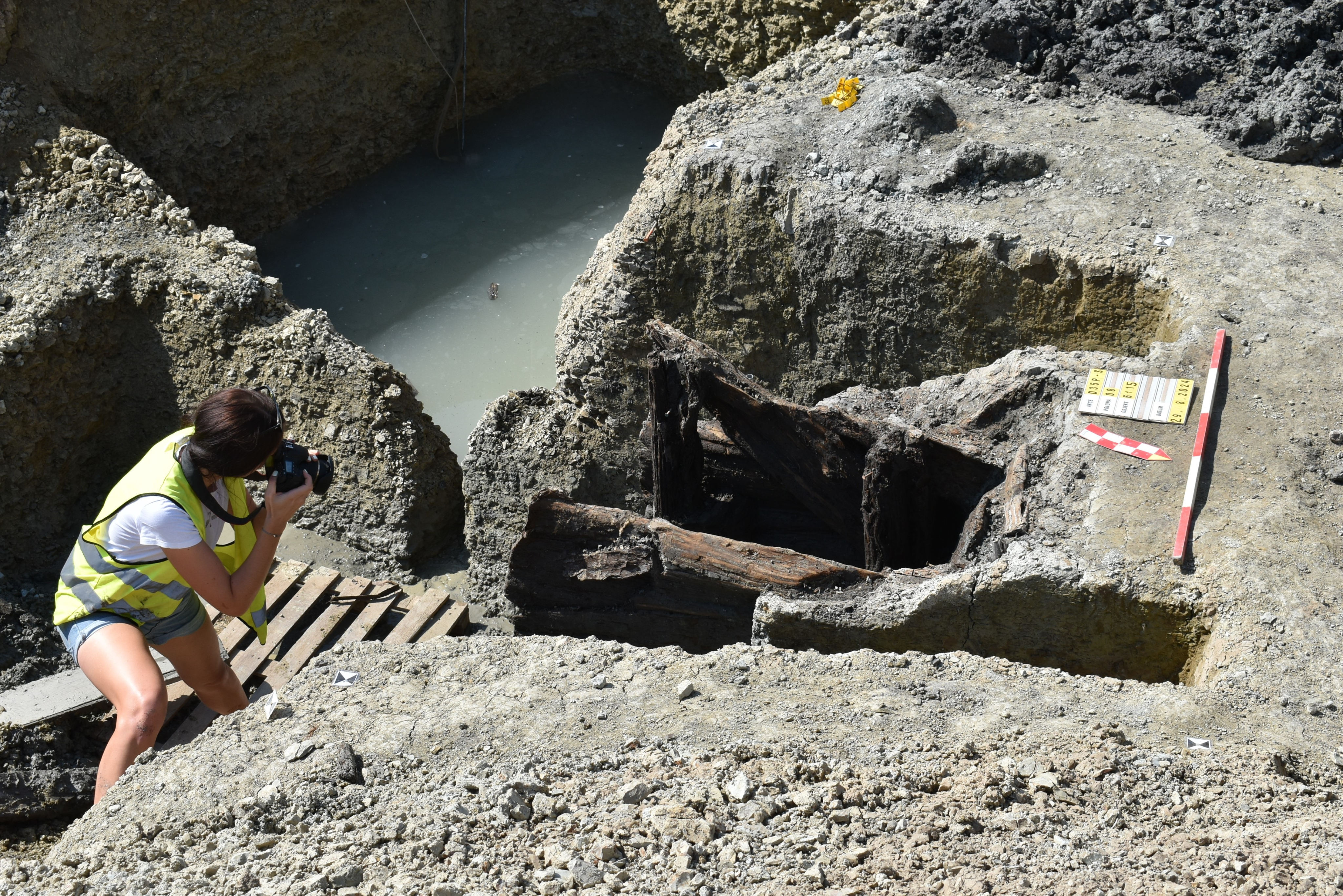 An archaeological excavation of Celtic settlement; an archaeologist takes photos of the site with a camera.