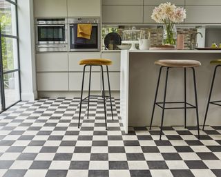 A kitchen with vinyl tile flooring in a grey and white checkered pattern