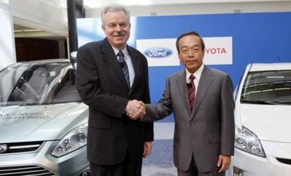 Top executives from Ford and Toyota shake hands during a news conference Monday, after announcing the car makers' collaboration on SUV hybrids.
