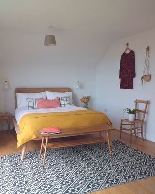 master bedroom with wooden bed and a yellow coloured throw