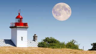 France. Normandie. Manche. Agon Coutainville. Rising of the full Moon above the lighthouse.