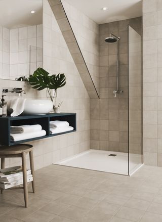 floor to ceiling seamless, cream coloured tiles in bathroom with shower, wall mounted sink and house plants