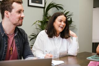 woman in a white shirt laughing next to a man at a desk