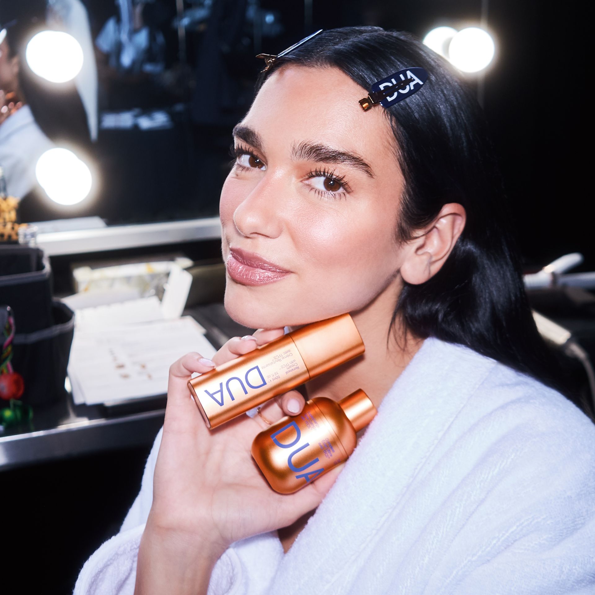 Dua Lipa holding her new DUA skincare products