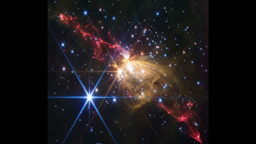 Streaks of red gas mix with young stars in the darkness of space as two large jets spew out on either side of a glowing yellow center, creating a magnificent nebula