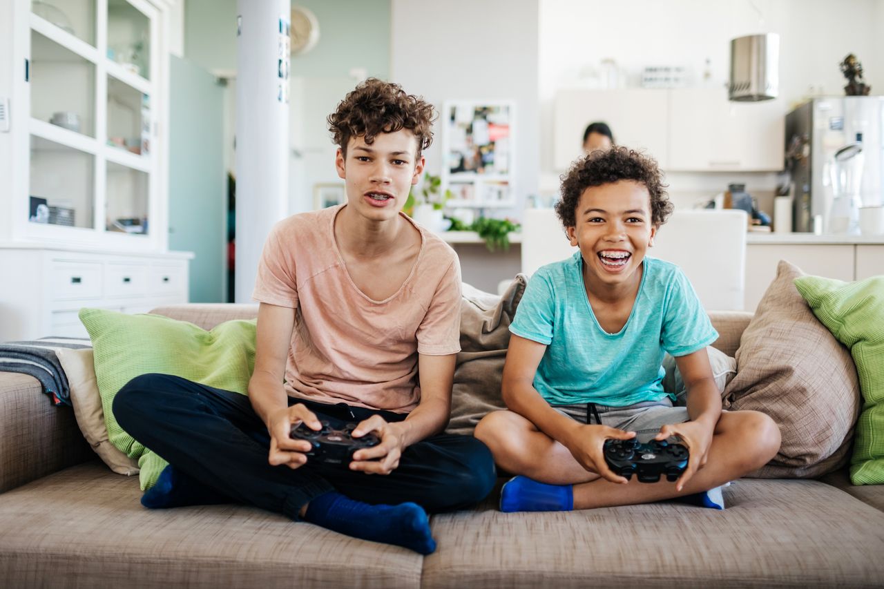 Two Brothers Sitting On Couch Playing Computer Games