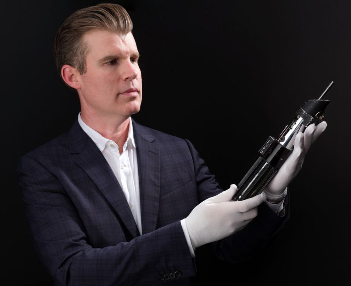 a man with white gloves holds a Star Wars prop