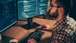 man working on computer displaying code