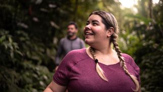 A woman smiling as she hikes through the forest