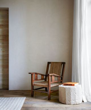 neutral living room with raw plaster walls and wooden chair