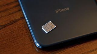 The back of an iPhone pictured with a sim card resting on it