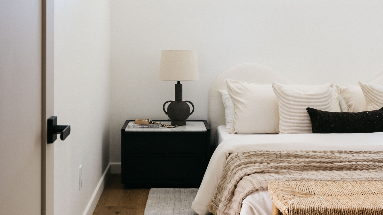 Image of a bedroom with neutral decor and a mix of textures used throughout the bedding and on the ottoman