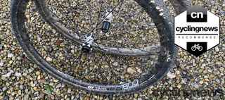 A pair of black dt swiss wheels with white logos on gravel surface