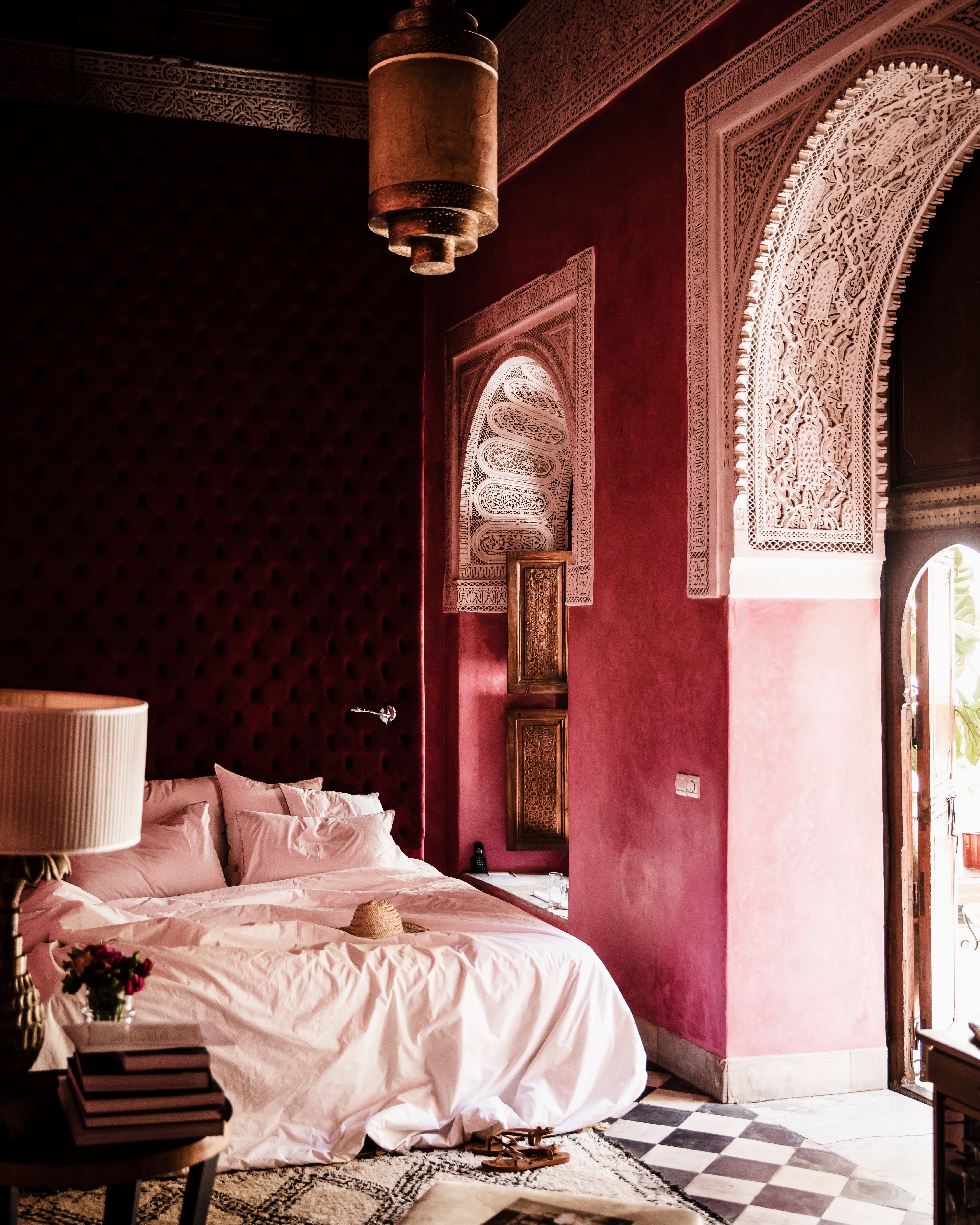 A layeredly decorated hotel room, adorned with traditional Moroccan reliefs and lamps and vintage furniture.