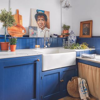 Bright blue kitchen with shaker cupboards, open shelving and belfast sink.