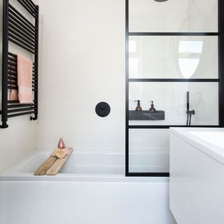 white built-in bath tub with black bathroom fittings in white bathroom