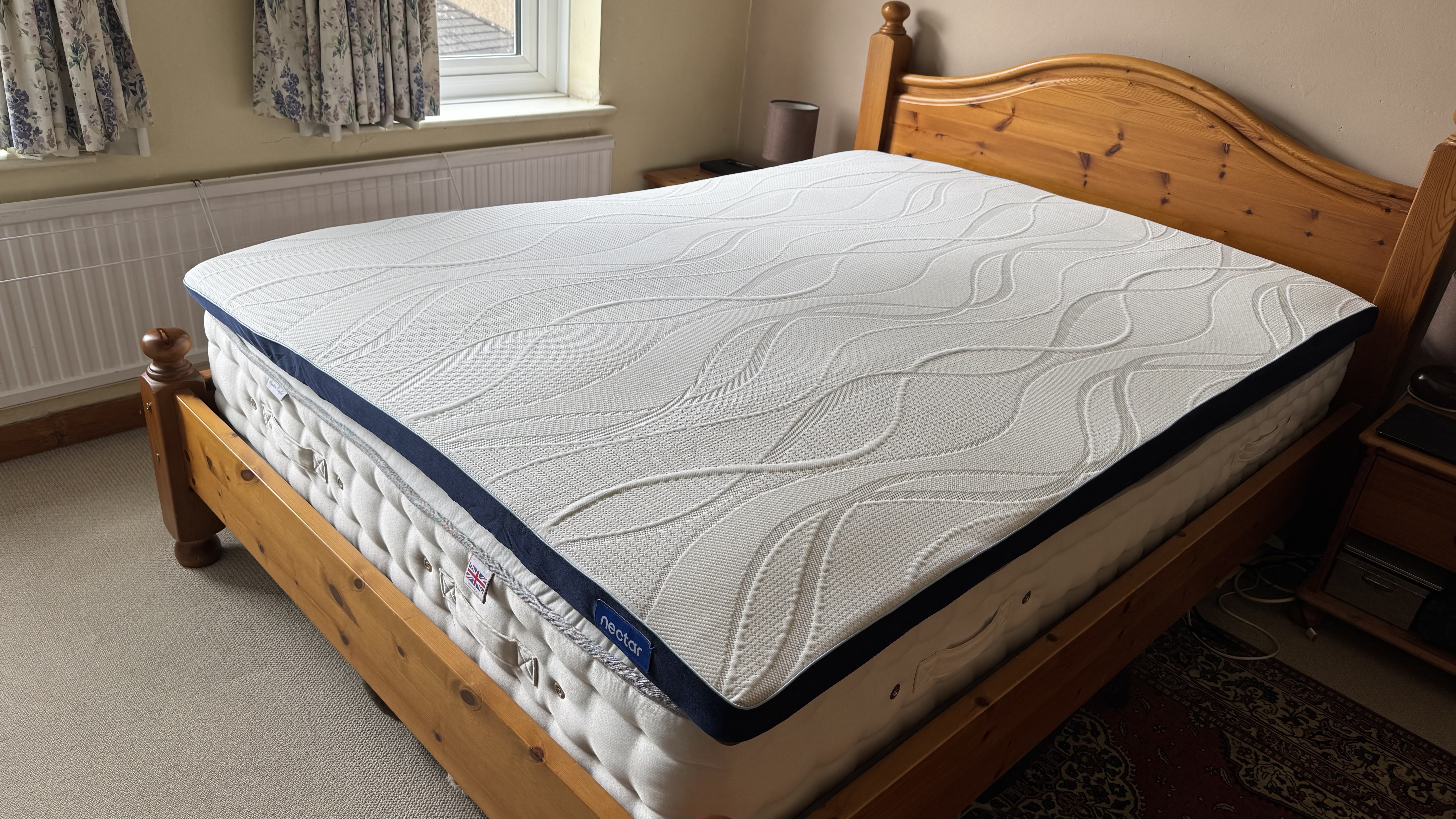 The Nectar mattress topper lying on a double mattress and pine bed.