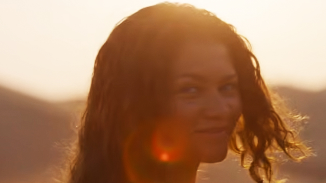 Zendaya looking back and smiling with the sun behind her.