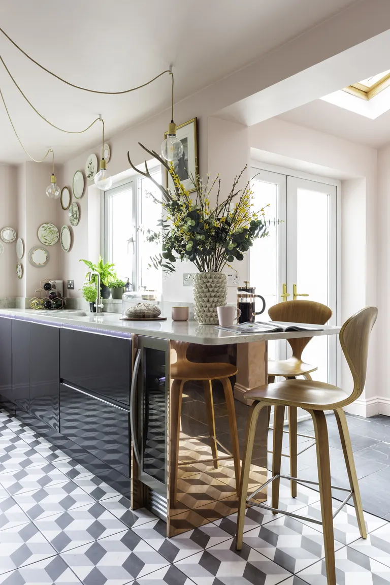 A bar area at the end of a run of kitchen units complete with copper coating and wooden bar stools