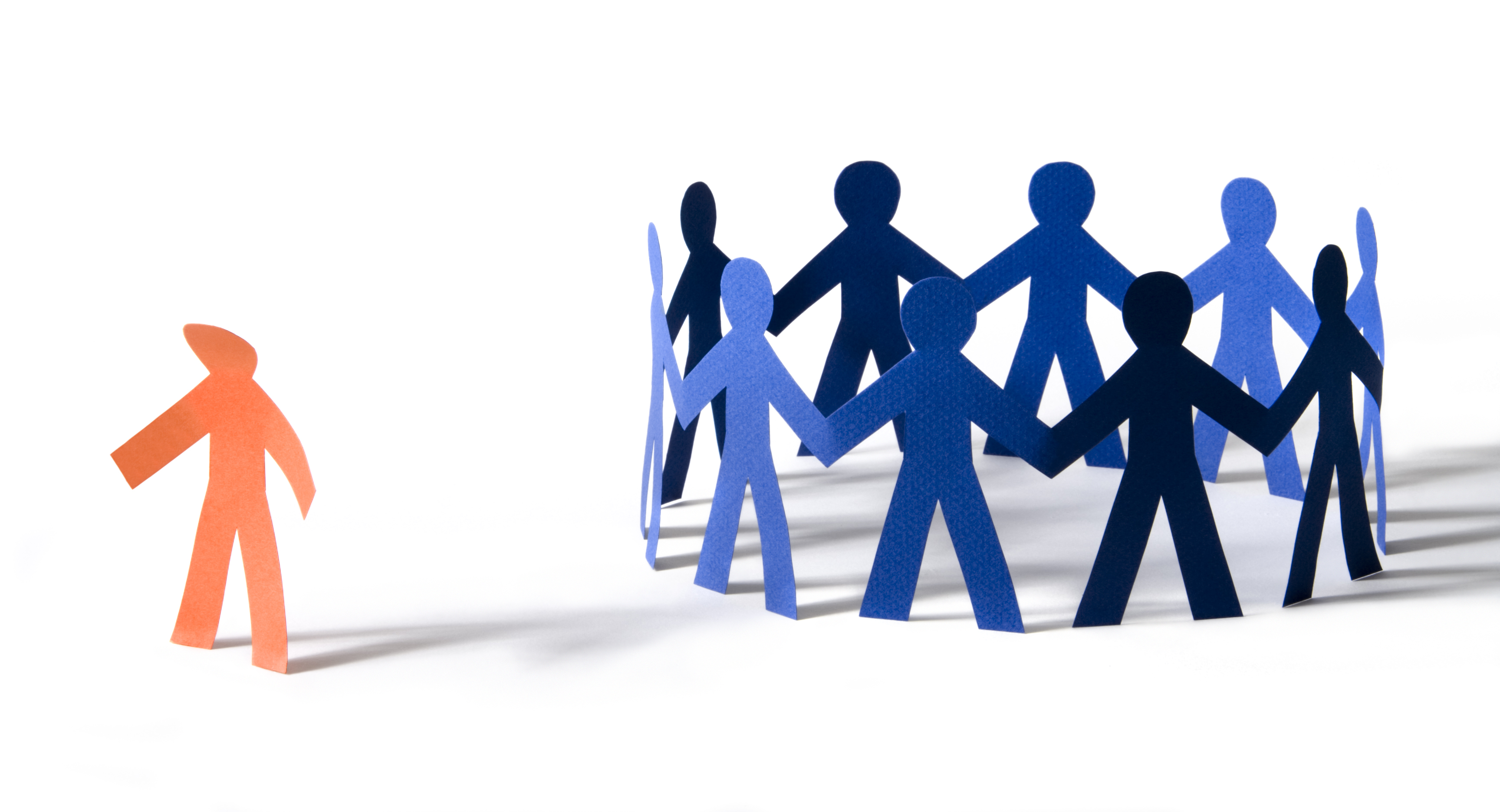 Exclusion hurts: Orange paper person with dejected stance off to the side of a circle of blue paper people. Isolated on white, with shadows.